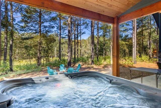 view of swimming pool with a forest view and a hot tub