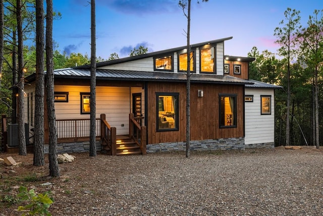 rear view of property with cooling unit, gravel driveway, a porch, crawl space, and metal roof