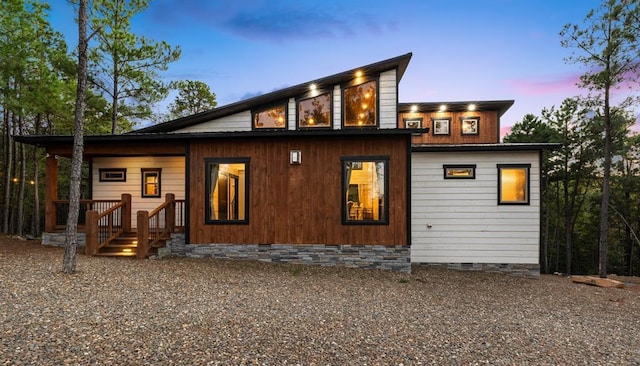 back of property at dusk featuring crawl space and driveway