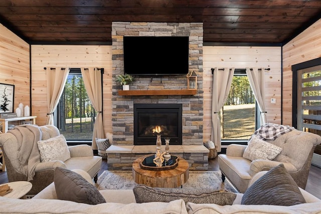 living area featuring a fireplace, vaulted ceiling, wooden walls, and wood ceiling