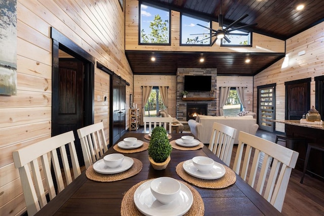 dining area featuring a fireplace, wooden walls, wood ceiling, and ceiling fan