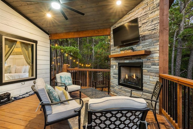 wooden terrace with a ceiling fan and an outdoor living space with a fireplace