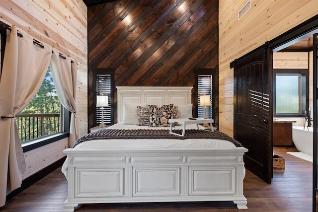 unfurnished bedroom featuring wood walls, a barn door, and dark wood-style flooring