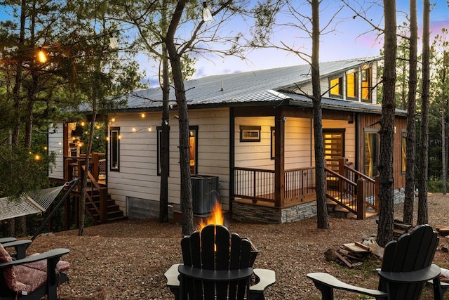 back of house at dusk with central air condition unit and metal roof