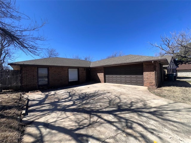 single story home featuring a garage, brick siding, fence, driveway, and roof with shingles