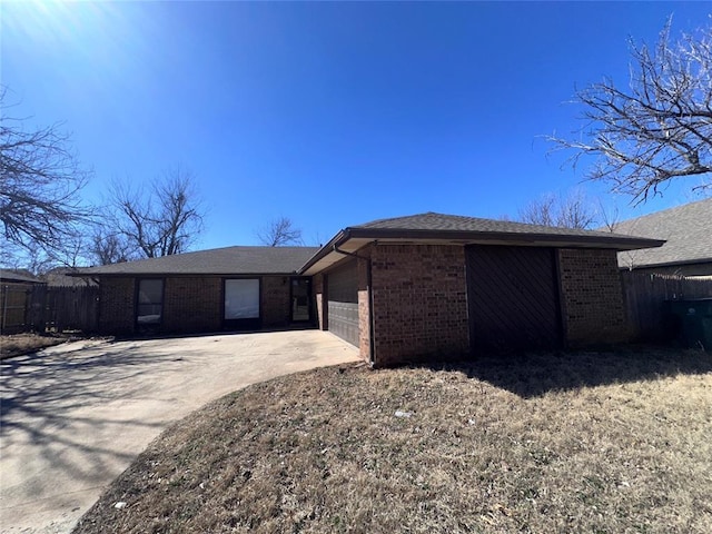 view of front of house featuring a garage, driveway, fence, and brick siding