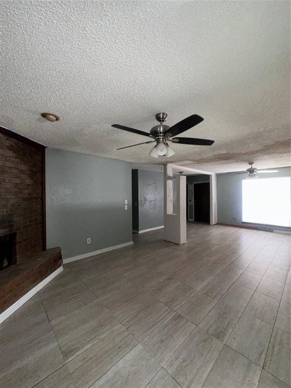 unfurnished living room featuring a fireplace, a textured ceiling, baseboards, and ceiling fan