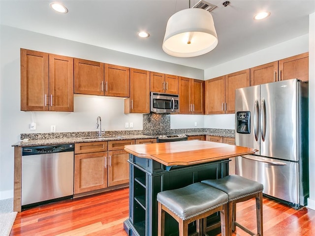 444 N Central Ave Unit 110, Oklahoma City, OK 73104 - kitchen featuring appliances with stainless steel finishes, a sink, light wood-style floors, brown cabinets, and recessed lighting