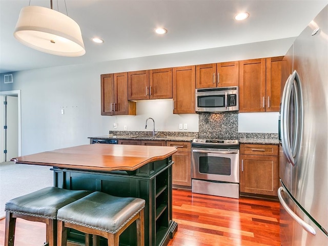 444 N Central Ave Unit 110, Oklahoma City, OK 73104 - kitchen with stainless steel appliances, a sink, a kitchen island, brown cabinets, and recessed lighting