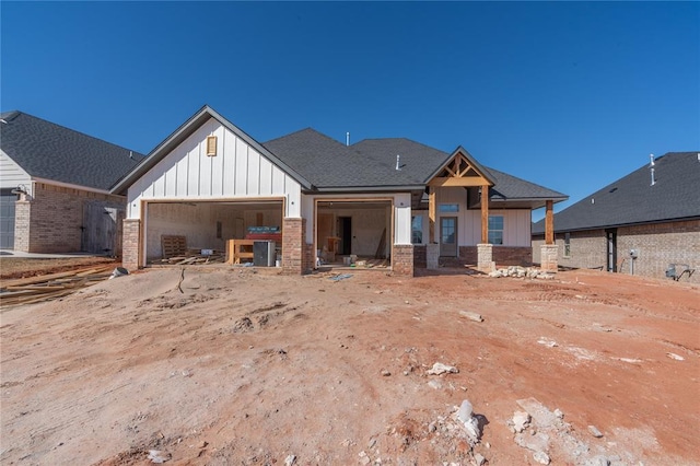 view of front of property featuring brick siding, board and batten siding, an attached garage, and a shingled roof