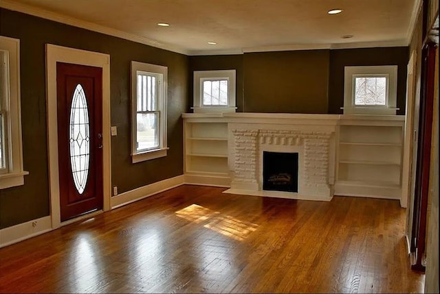 entryway with crown molding, a fireplace, baseboards, and wood finished floors