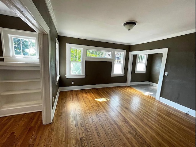 unfurnished room with hardwood / wood-style flooring, baseboards, and crown molding