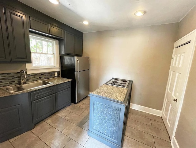 kitchen featuring recessed lighting, baseboards, freestanding refrigerator, a sink, and light tile patterned flooring