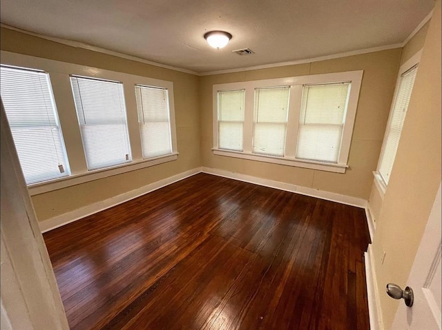 spare room with dark wood-type flooring, ornamental molding, and baseboards