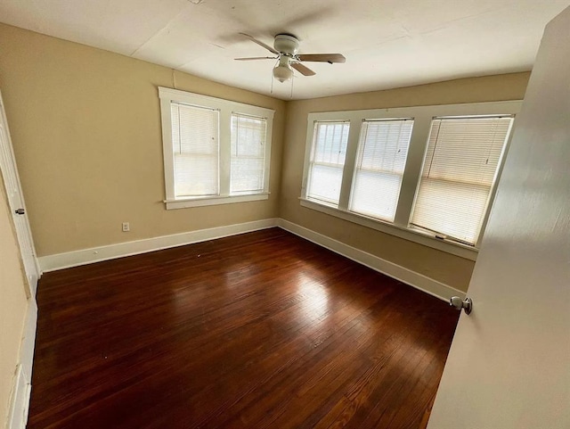 spare room with a ceiling fan, dark wood-style flooring, and baseboards