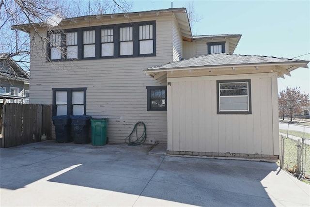 back of property with roof with shingles, fence, and a patio