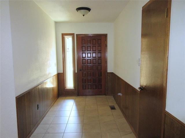 foyer entrance with visible vents, wainscoting, light tile patterned flooring, and wooden walls