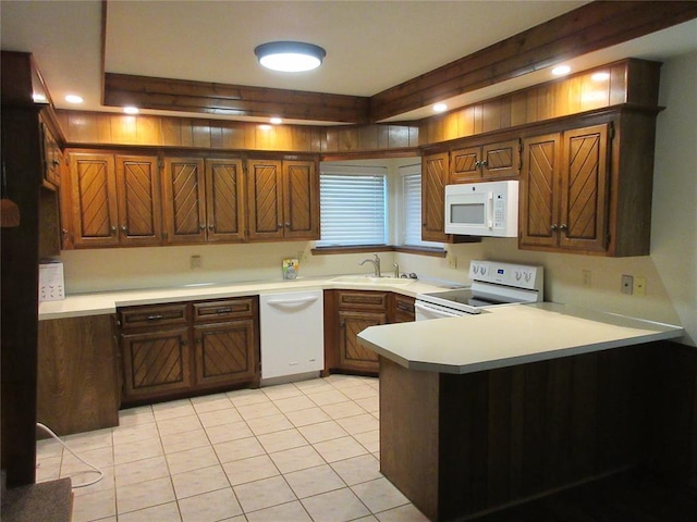 kitchen featuring white appliances, light countertops, a sink, and a peninsula