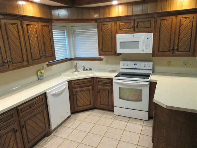 kitchen featuring light countertops, white appliances, light tile patterned flooring, and a sink