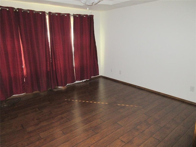 spare room featuring wood-type flooring and baseboards