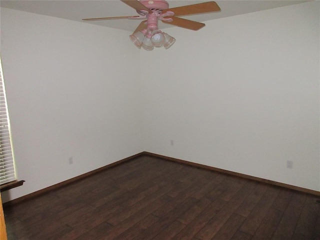 empty room with dark wood-type flooring, a ceiling fan, and baseboards