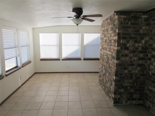 empty room with a ceiling fan, plenty of natural light, baseboards, and light tile patterned floors