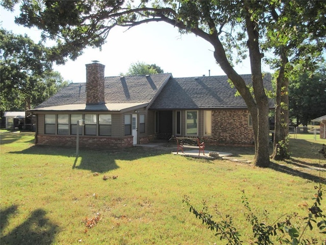 rear view of property with a patio area, brick siding, a yard, and a chimney