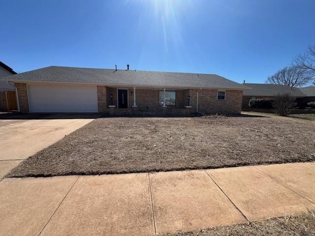 single story home with driveway, brick siding, and an attached garage