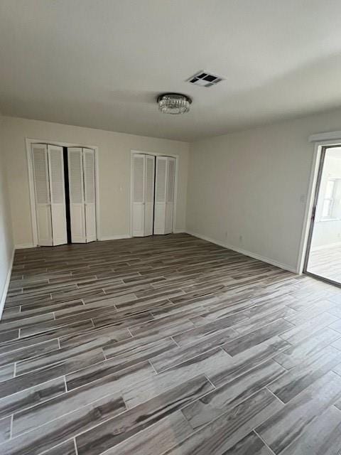 empty room featuring visible vents, dark wood finished floors, and baseboards