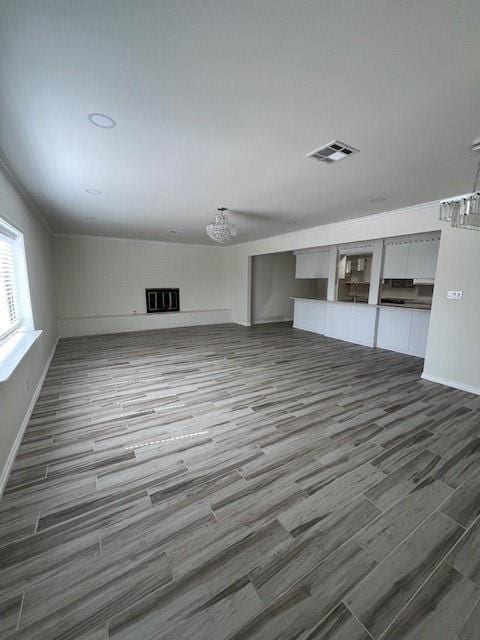 unfurnished living room featuring wood finished floors, visible vents, and baseboards