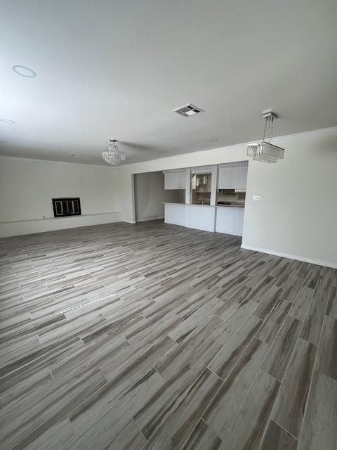 unfurnished living room featuring wood finished floors, visible vents, and baseboards