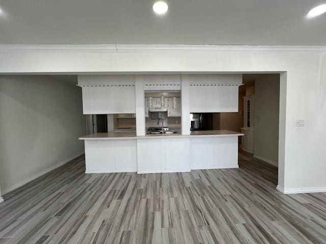 kitchen featuring wood finished floors, white cabinetry, baseboards, light countertops, and ornamental molding