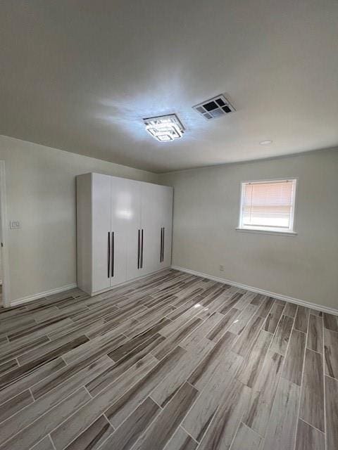 empty room featuring wood tiled floor, visible vents, and baseboards