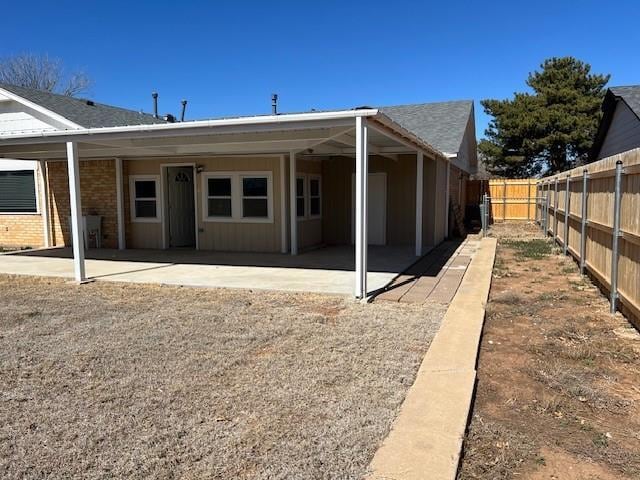 rear view of property featuring brick siding, fence, and a patio