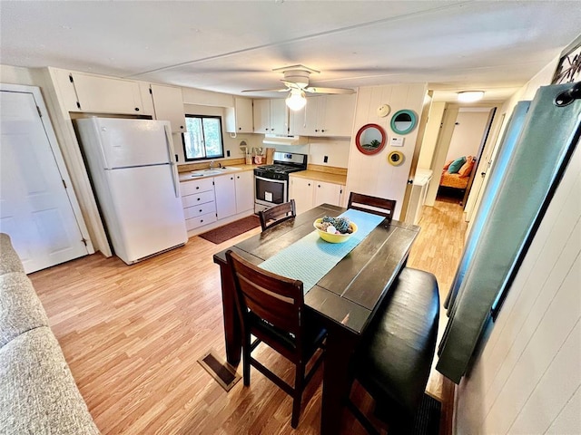 dining room featuring light wood finished floors, visible vents, and a ceiling fan