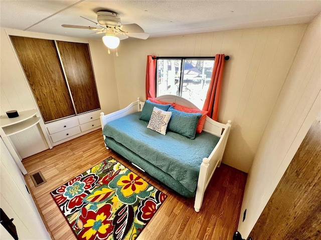 bedroom with ceiling fan, visible vents, and wood finished floors
