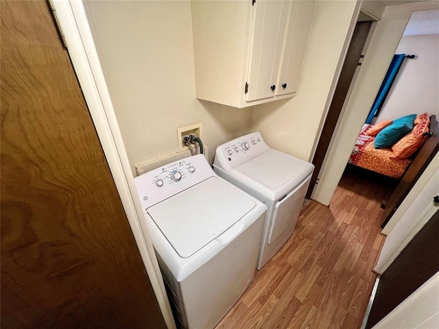 clothes washing area featuring cabinet space, light wood finished floors, and separate washer and dryer