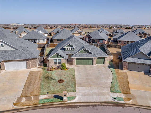 view of front of house with an attached garage, brick siding, driveway, roof with shingles, and a residential view