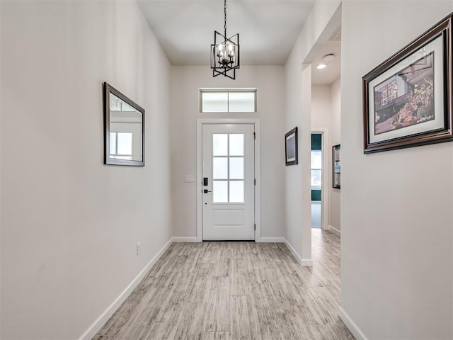 entrance foyer with light wood-style flooring, baseboards, and a chandelier