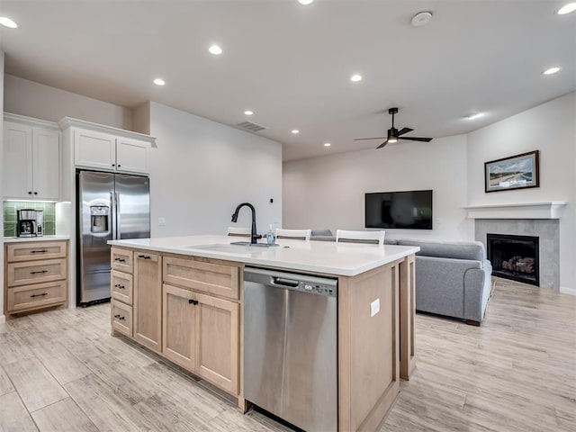 kitchen with light brown cabinets, a kitchen island with sink, stainless steel appliances, a sink, and light countertops