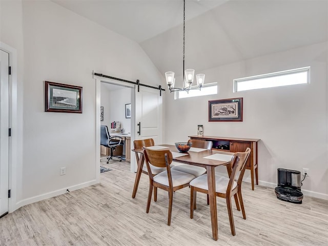 dining area with lofted ceiling, a barn door, light wood-style flooring, and baseboards