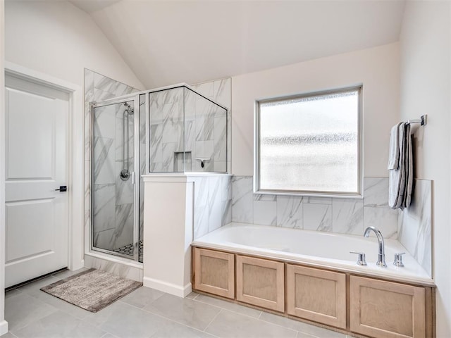 bathroom featuring a stall shower, tile patterned flooring, a garden tub, and vaulted ceiling