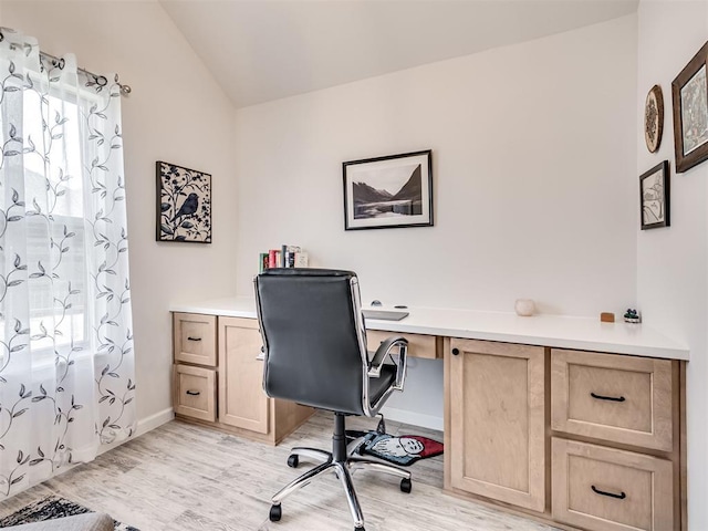 office space with lofted ceiling, baseboards, and light wood-style floors