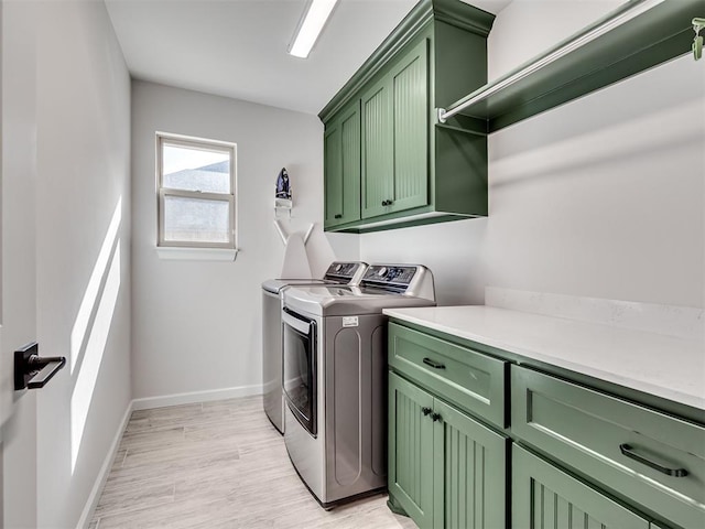 washroom with cabinet space, light wood-style flooring, baseboards, and washer and clothes dryer