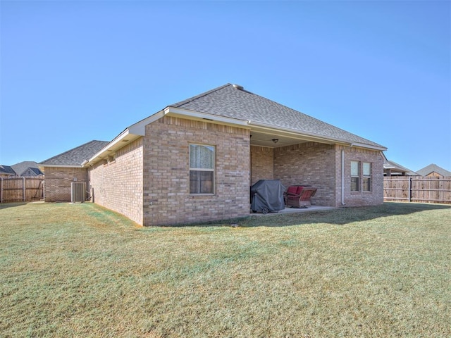 rear view of property with a yard, a fenced backyard, and central air condition unit