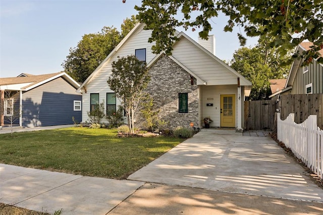 view of front facade with driveway, a front yard, and fence