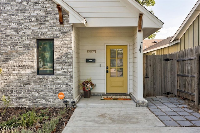 entrance to property with fence and brick siding