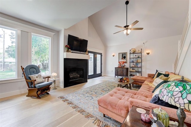 living area with high vaulted ceiling, light wood-type flooring, a fireplace, and baseboards