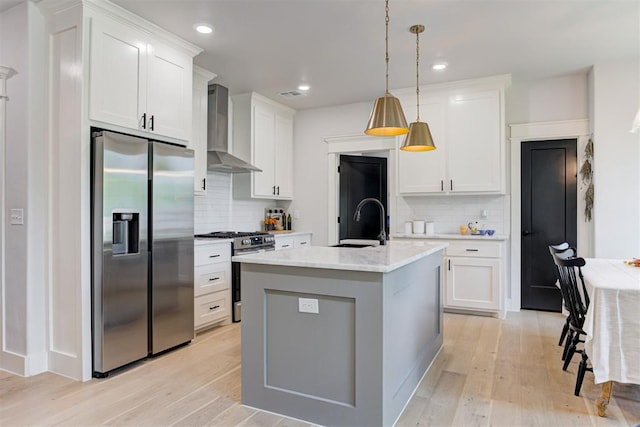 kitchen featuring wall chimney exhaust hood, appliances with stainless steel finishes, light wood-type flooring, and a sink