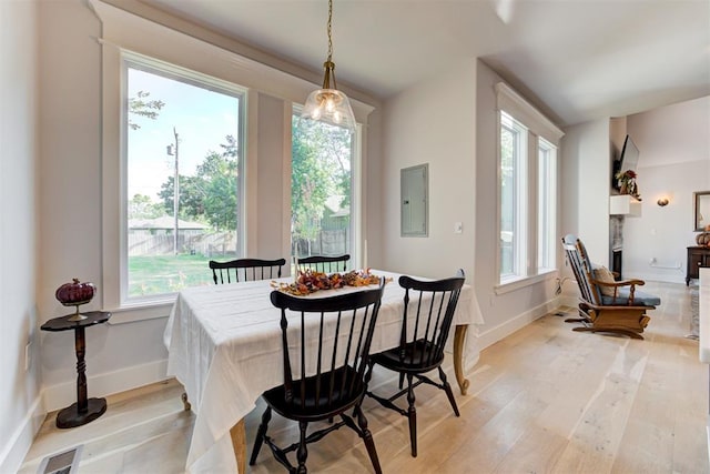 dining area with visible vents, electric panel, light wood-style flooring, and baseboards